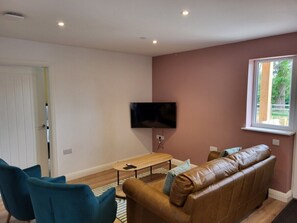A modern living room with a sofa, chairs, a coffee table, and a TV mounted on the wall.