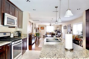 A spacious kitchen with granite countertops, stainless steel appliances, and pendant lighting. - Charming Craftsman Retreat: 3BR Home w/ Pool & Jacuzzi – Your Perfect Getaway! (Bonita)