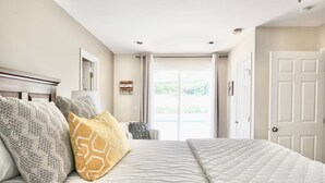 A bedroom with a large bed, a nightstand, and a window with curtains. - Charming Craftsman Retreat: 3BR Home w/ Pool & Jacuzzi – Your Perfect Getaway! (Bonita)