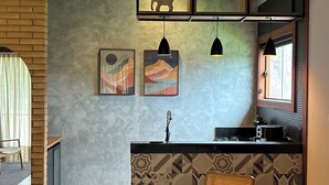A modern kitchen with a dining area, featuring a round table, wooden chairs, and a hanging light fixture. - Green Village - Luxury and Comfort you are looking for! (Corrêas Petrópolis)