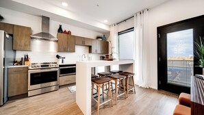 A modern kitchen with wooden cabinets, stainless steel appliances, and a central island with bar stools.