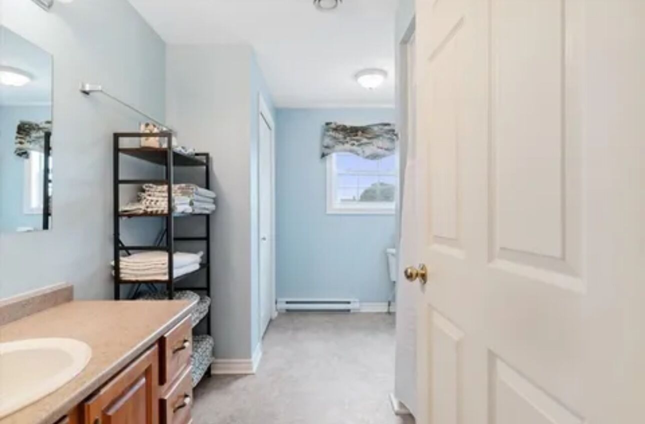 A bathroom with a sink, a towel rack, and a door leading to another room.