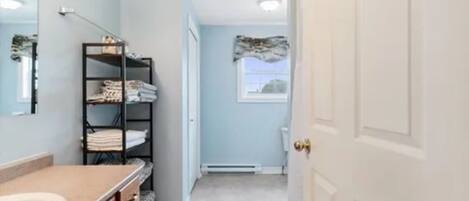 A bathroom with a sink, a towel rack, and a door leading to another room.