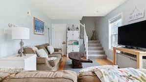 Ein Wohnzimmer mit einer Couch, einem Couchtisch, einem Fernseher und einer Treppe, die zu einer anderen Ebene führt.