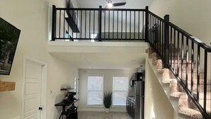A spacious living area with a high ceiling, a staircase, and a dining area. - Captivating 2-bedroom, garage door house with WiFi, AC in welcoming Somerset  (Somerset)