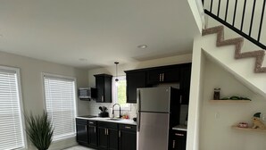 A modern kitchen with dark cabinets, a stainless steel refrigerator, and a dining area with a table and chairs. - Captivating 2-bedroom, garage door house with WiFi, AC in welcoming Somerset  (Somerset)