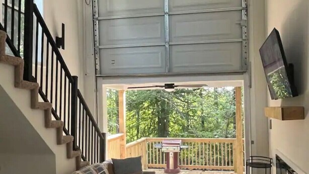 A spacious living room with a brown leather sofa, a patterned rug, a wooden staircase, and a balcony with a grill. - Captivating 2-bedroom, garage door house with WiFi, AC in welcoming Somerset  (Somerset)