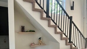 A living room with a brown leather sofa, a plaid throw pillow, a small dog on a shelf, and a staircase with a stone accent. - Captivating 2-bedroom, garage door house with WiFi, AC in welcoming Somerset  (Somerset)