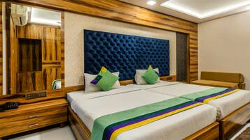 Uma cama de casal com cabeceira acolchoada, mesas de cabeceira de madeira, um espelho e uma mesinha de apoio com um telefone.