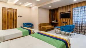 A hotel room with two beds, a sofa, a TV, and a wooden wall. - Hotel Orion Crystal (Kolkata)