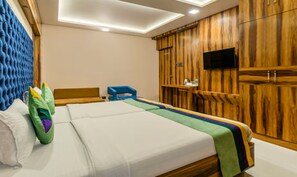 Une chambre d’hôtel avec un lit, une télévision, des panneaux de bois au mur et un luminaire au plafond.