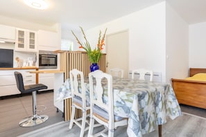 A modern kitchen with white cabinets, a built-in oven, and a dining area with a table set for four.