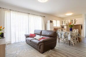 A living room with a sofa, dining table, and kitchen area.