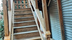 Una escalera de madera con barandilla de metal que lleva a la puerta de un garaje.
