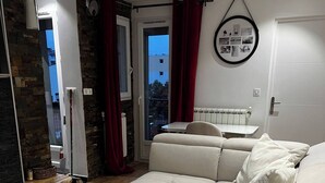 A modern living room with a sectional sofa, a wooden coffee table, and a view through a glass door. - Cosy apartment with views over Paris (Le Kremlin-Bicêtre)