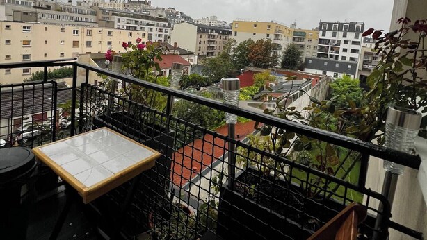 A balcony with a table and chairs, overlooking a residential area with various buildings. - Cosy apartment with views over Paris (Le Kremlin-Bicêtre)