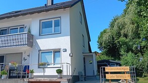 A two-story house with a balcony, a garage door, and a sign indicating it's a rental property. - Ferienwohnung am Weiher – Ihr perfektes Urlaubsdomizil für die ganze Familie! (Denklingen)