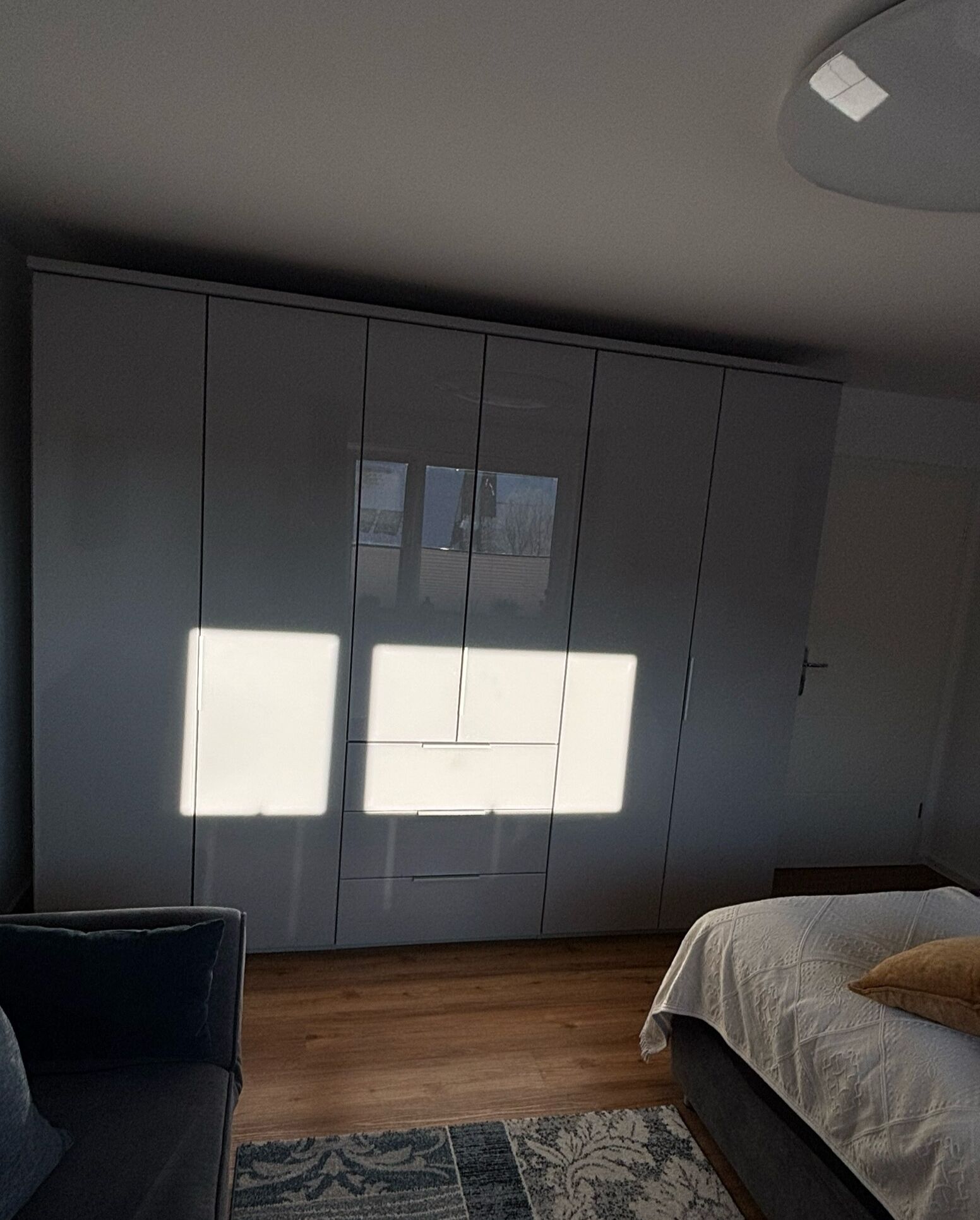 Une chambre avec une grande armoire, un lit avec un oreiller marron et un tapis à motifs.
