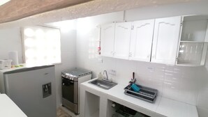 A compact kitchen with white cabinets, a stainless steel stove, and a sink.
