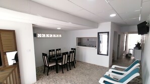 A spacious room with a dining area, a kitchen, and a seating area with chairs and a sofa.