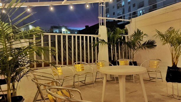 An outdoor patio area with metal chairs and a table, surrounded by potted plants.