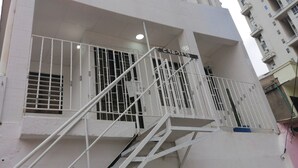 A multi-story building with a white facade, a metal staircase with railings, and a visible fire escape.