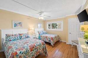 A bedroom with two beds, a ceiling fan, a window with blinds, and a door. - 3 Bedroom Beachfront Condo with Pool and Hot Tub (Panama City Beach)