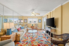 A living room with a sofa, chairs, a television, and a patterned rug. - 3 Bedroom Beachfront Condo with Pool and Hot Tub (Panama City Beach)