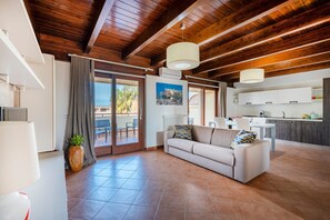 A modern living room with a sofa, a dining area, and a kitchen.