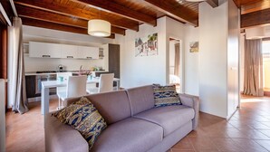 A modern living room with a sofa, a dining area, and a kitchen in the background. - 'Attico da Mare 14' Apartment with Private Terrace, Wi-Fi and Air Conditioning (Polignano a Mare)
