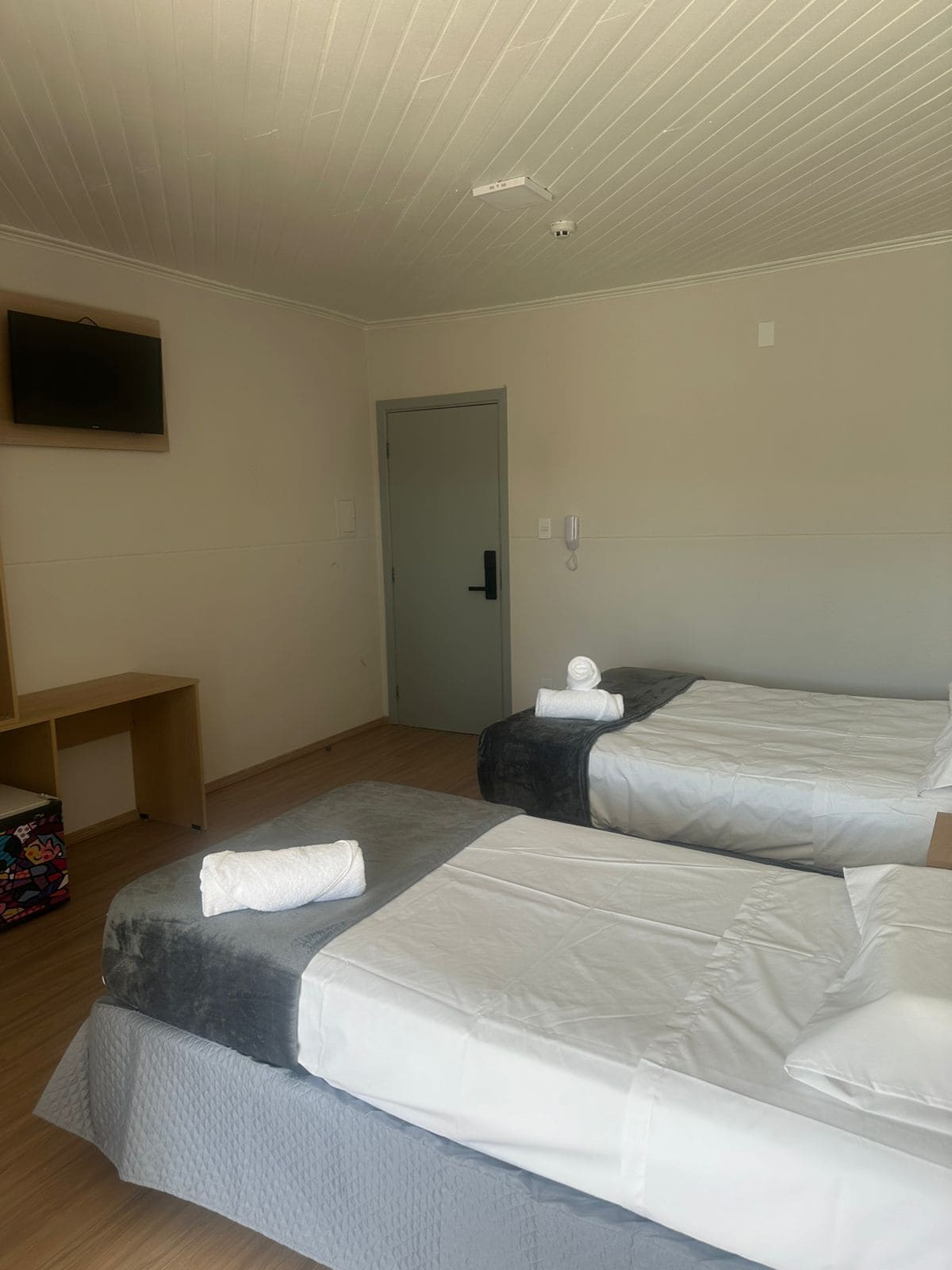 Une chambre d’hôtel avec deux lits, un bureau, une télévision et une porte.