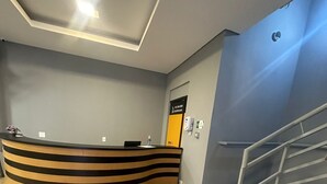 A reception desk with a modern design, a staircase, and a clean, well-lit interior. - Unity Hotel Votorantim (Votorantim)