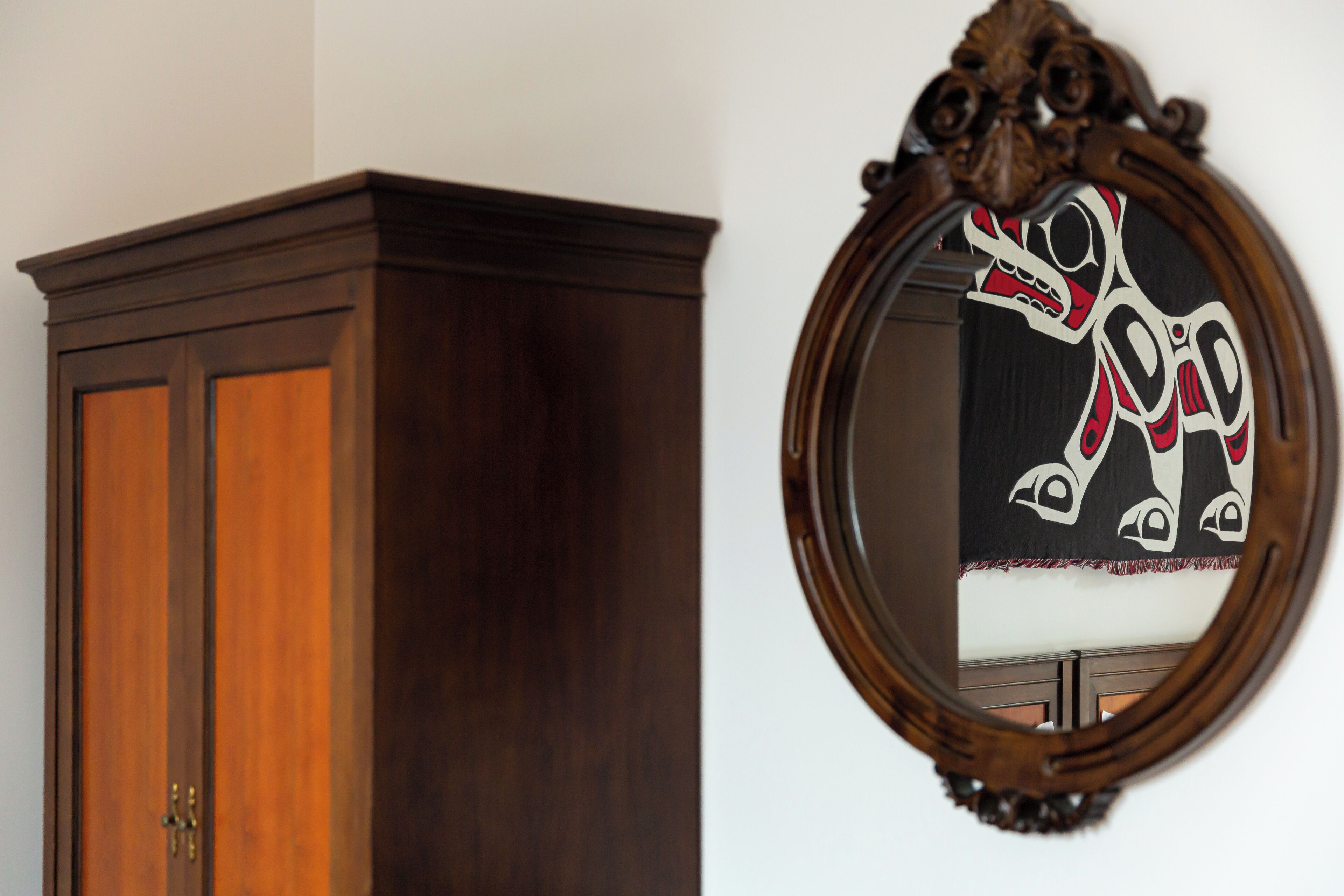 A wooden wardrobe and a mirror with a decorative frame.