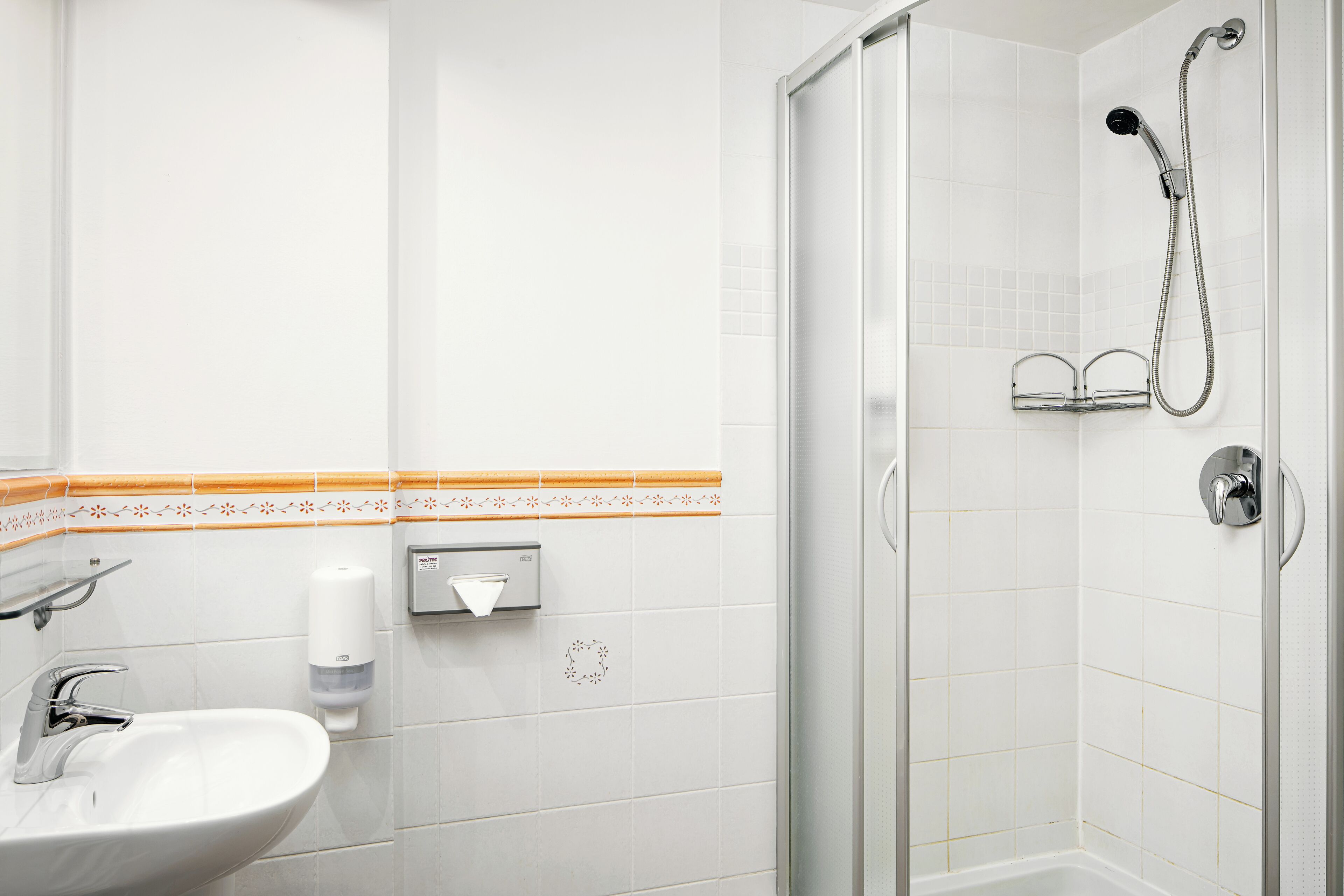 Een badkamer met een wastafel, een handdroger en een douche met een flexibele douchekop.