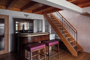 Una cocina con taburetes de madera, una escalera de madera y vistas al exterior.