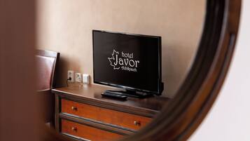 Um espelho reflete um quarto com uma cômoda de madeira, um quadro na parede e uma placa com a inscrição 'hotel Javor Drápach'.