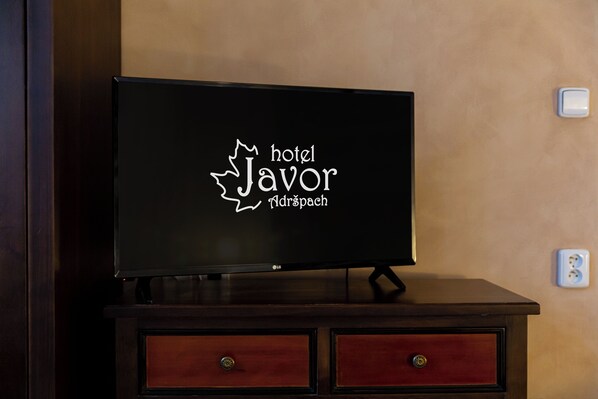 A flat-screen TV on a wooden dresser with a logo for 'hotel Javor' and 'Narspace' displayed on the screen. - Hotel Javor (Adrspach)