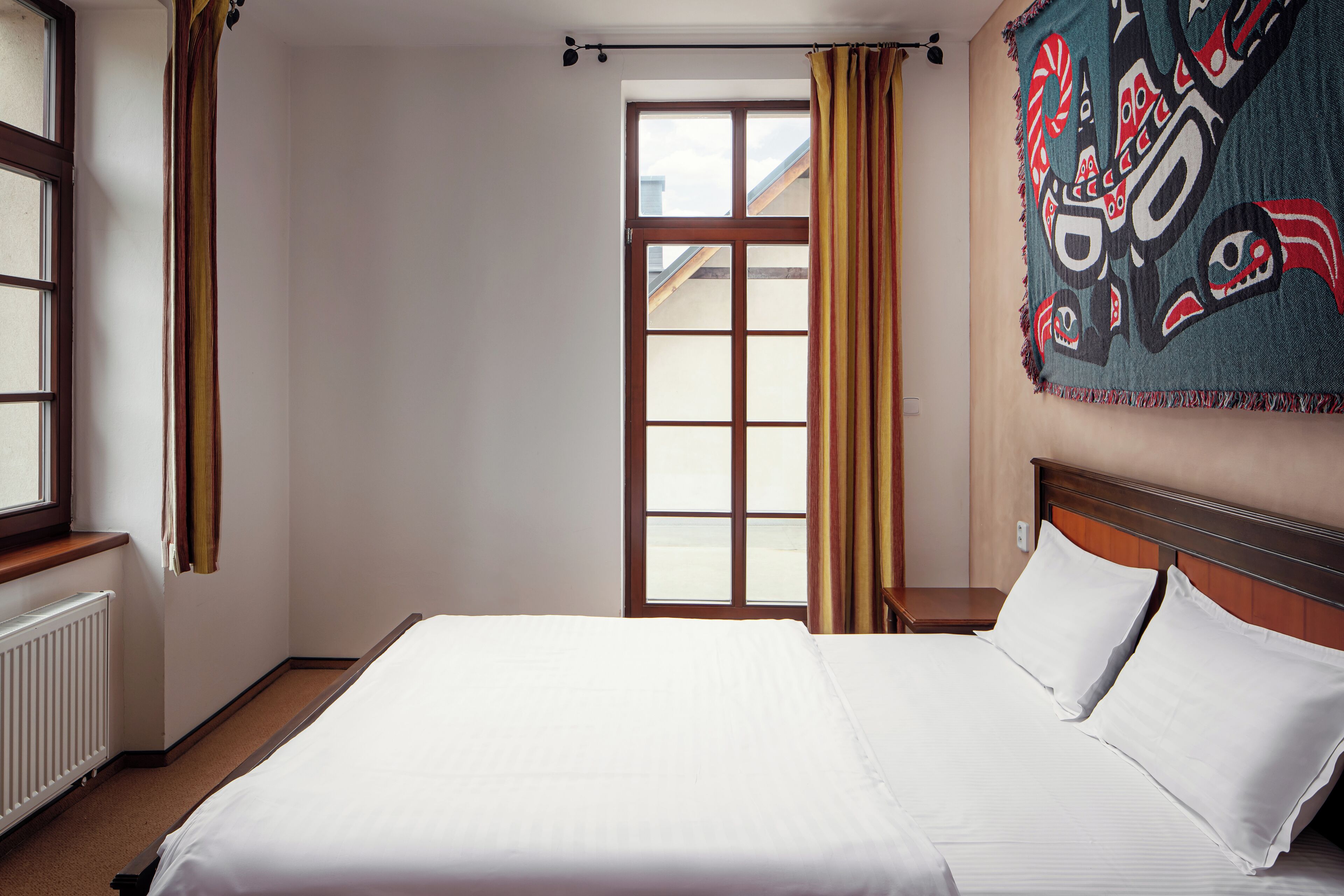 A hotel room with a large bed, a window with curtains, and a view of the outside.