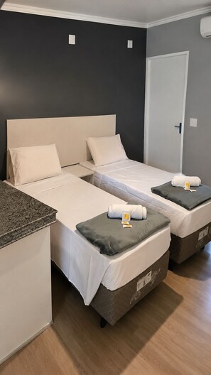 Ein Zimmer mit zwei Betten, einer kleinen Küchenzeile und einer Tür.