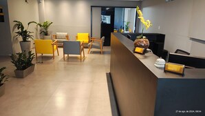 Un espace d’accueil moderne, avec un comptoir de réception, plusieurs chaises et des plantes en pot.