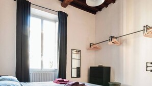 A bedroom with a bed, a dresser, a mirror, and a hanging light fixture. - Apartmens in Florence Via Porte Nuove (Firenze)