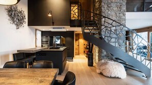 A modern kitchen with a central island, a dining area with a wooden table, and a spiral staircase leading to an upper level.