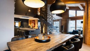 A modern dining area with a wooden table, black chairs, and pendant lighting.