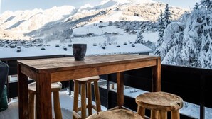 A wooden table with a vase on a balcony overlooking a snowy mountain landscape.