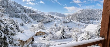 A snow-covered landscape with a wooden cabin and a wooden balcony railing.