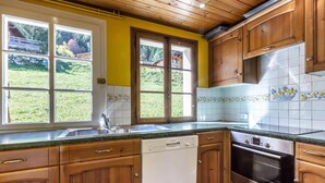 Une cuisine avec des meubles de rangement en bois, un lave-vaisselle, un four et un évier.