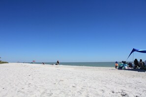 A beach with a clear sky, people, and a tent.