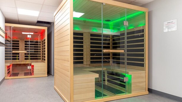 Ein moderner, geschlossener Stauraum mit Glastüren und Holzböden, ausgestattet mit grünem, indirektem Licht.