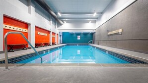 Ein Hallenbad mit deutlichen Bahnen, ein Umkleidebereich mit orangefarbenen Wänden und eine blaue Wand im Hintergrund.