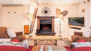 Ein gemütliches Wohnzimmer mit Kamin, bequemen Sitzgelegenheiten und einem Fernseher.